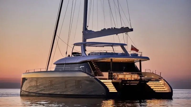 A sailing catamaran on calm water at dusk