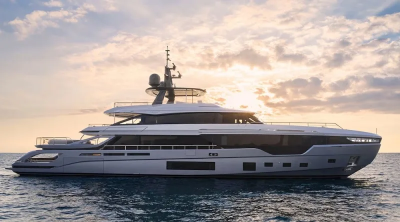 A tri-deck superyacht at sea at sunset